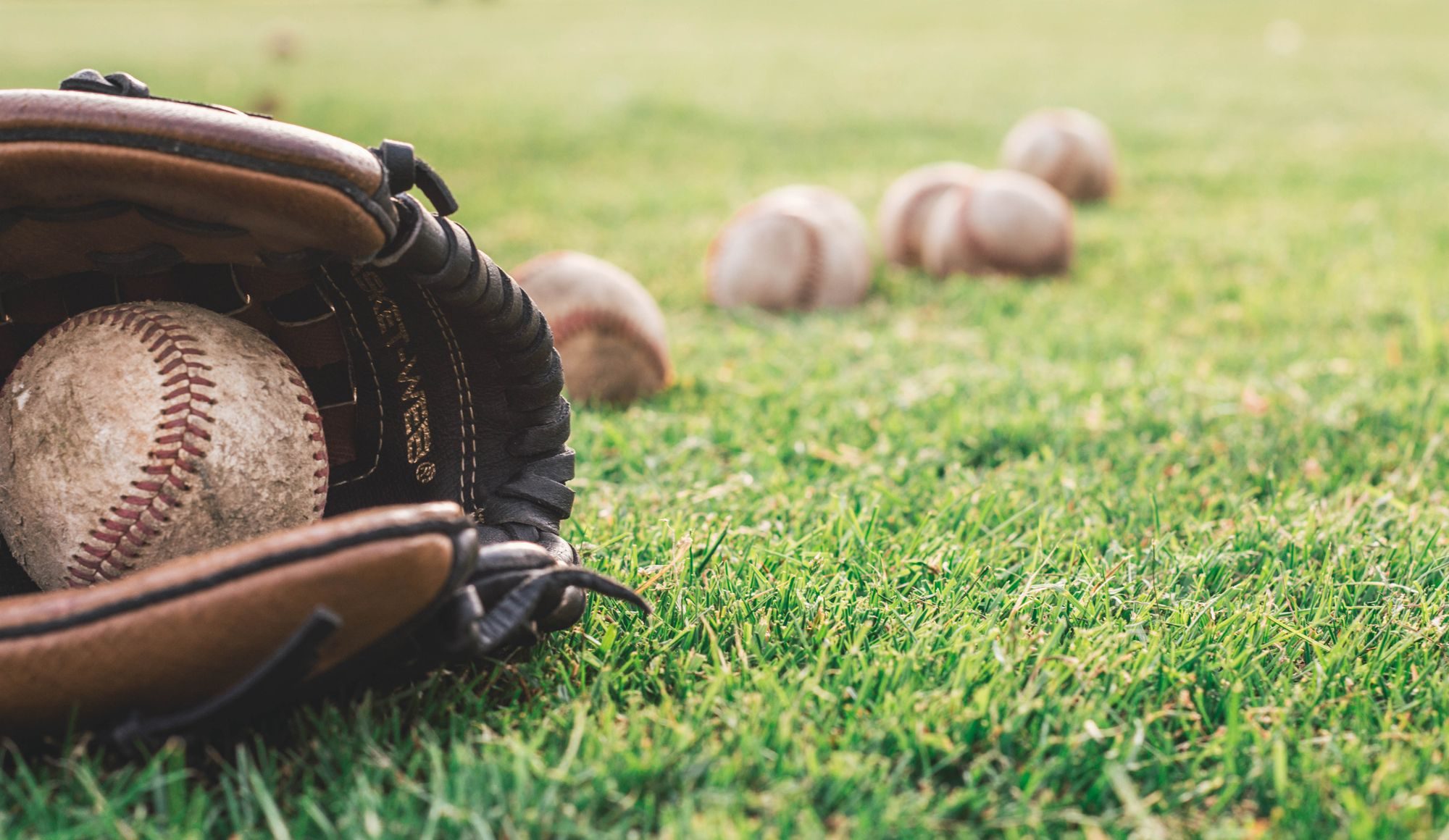 A baseball glove and balls on grass